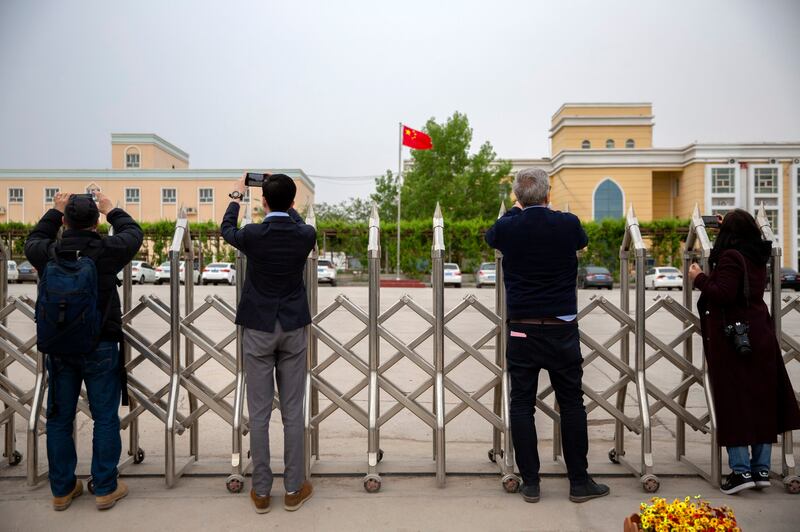 Journalists take photos outside a location identified in early 2020 as a re-education facility, which the Chinese government asserts is home to a veterans' affairs bureau and other offices, in western China's Xinjiang Uyghur Autonomous Region, during a trip organized by the government for foreign journalists, April 22, 2021. Credit: AP Photo