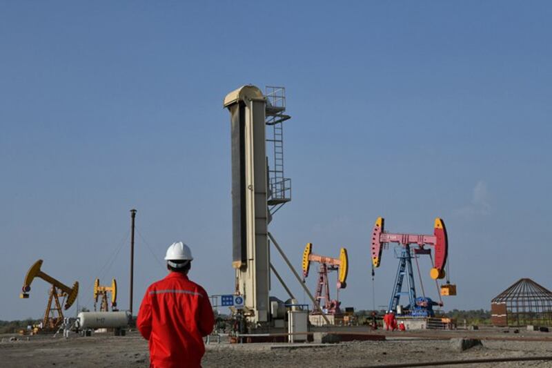 Workers are seen near pumpjacks at a China National Petroleum Corp oil field in Bayingol in northwestern China's Xinjiang region, Aug. 7, 2019. (Reuters)
