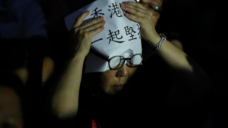 一名香港民众在头上放着“香港 一起坚持”的标语。(美联社)