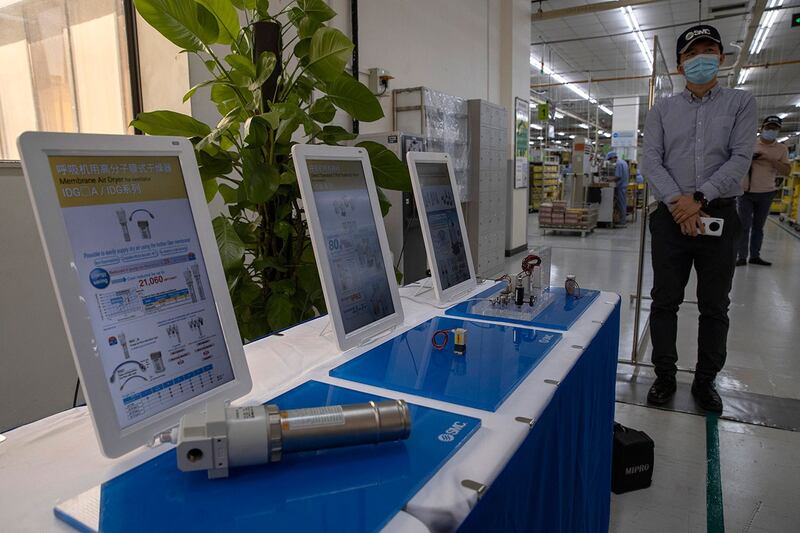 资料图片:2020 年 5 月 13 日,日本气动工程公司 SMC 的一名员工站在北京一家工厂生产的呼吸机零件的展示附近。(美联社)