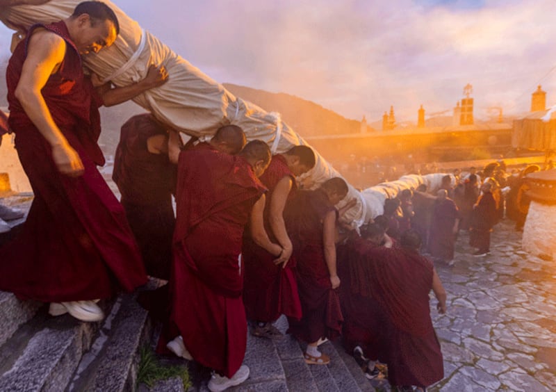 Tibetan Buddhist monks carry a enormous rolled-up thangka painting of Buddha at the Drepung Monastery in Lhasa, capital of western China's Tibet Autonomous Region, Aug. 4, 2024. (Jiang Fan/Xinhua via Getty Images)