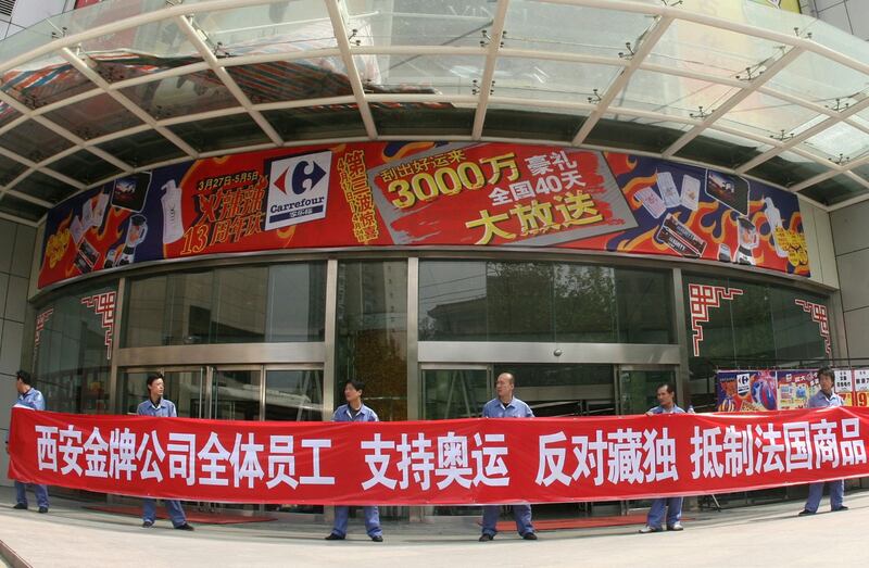 资料图片：2008年4月17日，当地公司的员工在陕西省西安家乐福超市外面举着“支持奥运会，反对西藏独立，抵制法国商品”的横幅。（路透社）