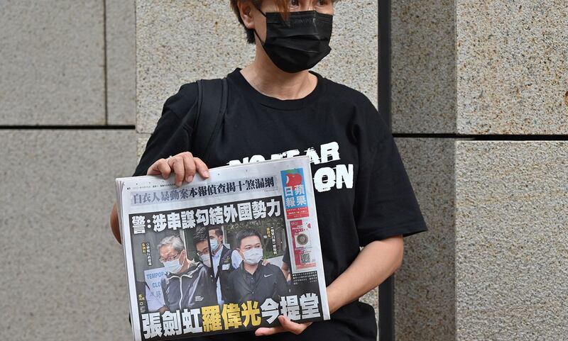 学者认为对传媒打压只是刚开始。图为,香港市民手持《苹果日报》在法庭外的抗议。(法新社)