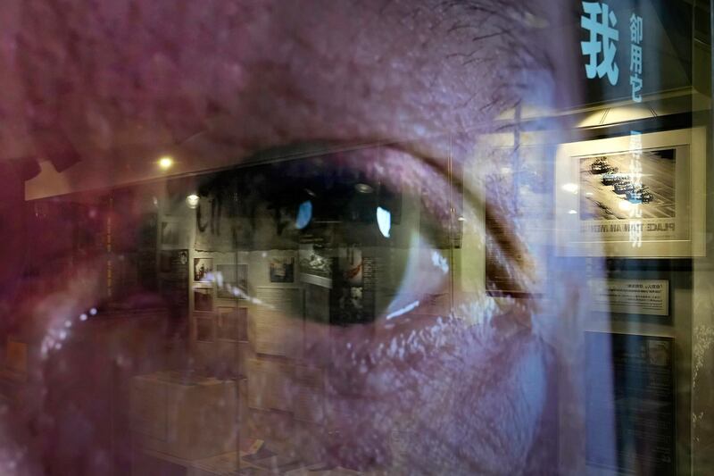 资料图片:一名民众的眼睛出现在电视屏幕上,一幅幅描绘 1989 年北京民主运动中图片在香港“六四纪念馆”展出。(美联社) .