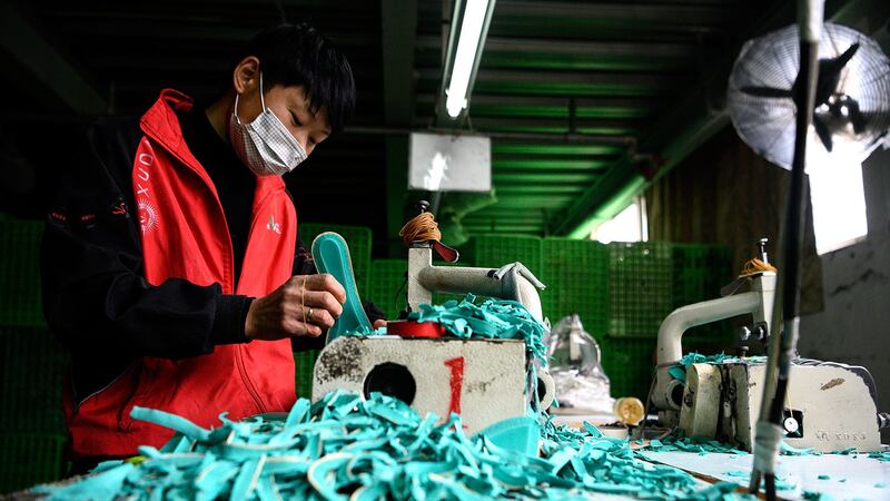 图为工人在浙江温州一家鞋业有限公司的厂房制造鞋垫。(法新社)