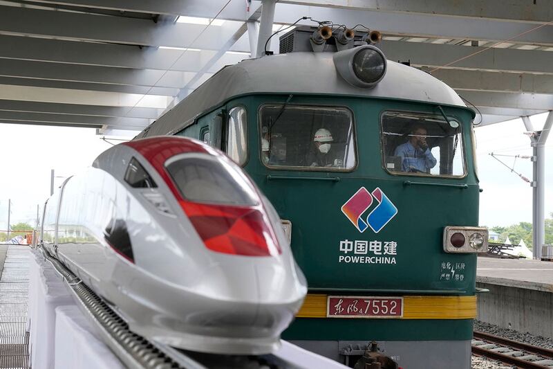 2022年10月13日,在印度尼西亚西爪哇省 Tegalluar 的雅加达-万隆快速火车站的建筑工地上,一辆火车引擎驶过展示的高速列车模型。(美联社)