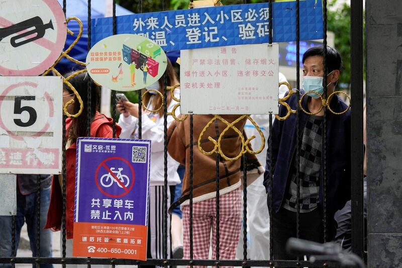 2022 年 4 月 13 日,中国上海,在冠状病毒病大流行期间,一名等待送餐的居民从封锁住宅区入口向外望去。(路透社)